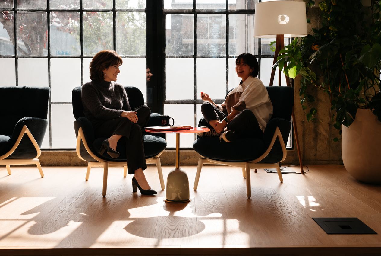 Michele Smith talking with a client in a sunlit lounge, long window shadows across the floor